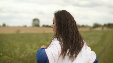 25 yaşında sportif görünümlü bir kız gölün yanındaki parkta ısınıyor.