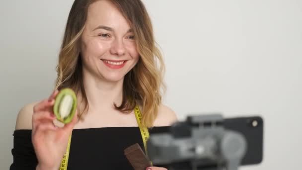 Egy fiatal diétás nő kiwit és gofrit tart a kezében, és edz.. — Stock videók