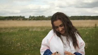 Güzel, mutlu bir kız gölün arka planında müzik dinliyor kulaklıklarla dans ediyor.