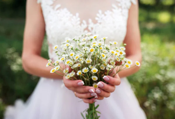summer bouquet of field daisies in the hands of a bride