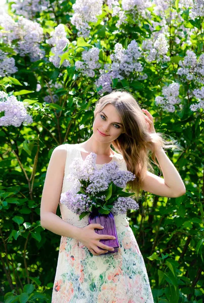 美丽的女人穿着夏装 一束紫丁香在一个盛开的花园里 自然美而无妆容 — 图库照片