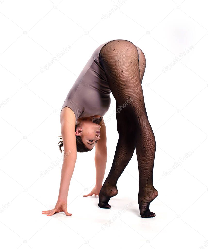 A gymnast in a bodysuit performs a head-down stand. Training elements of acrobatics on a white background. Stretching exercises.