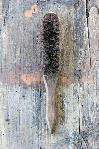 Old, dirty wire brush against wooden plank. Tool series.