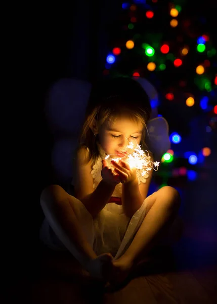 Girl in a dark room with bright garland lights. irl makes a wish on New Year\'s Eve. Waiting for a miracle. girl holds lights in hands