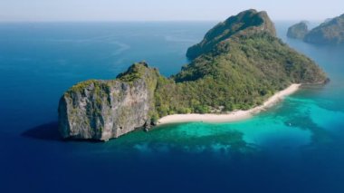 Filipinler 'de beyaz kumsal yeşil ormanı ve mercan resifi turistik rotası olan egzotik bir adanın insansız hava aracı görüntüsü.