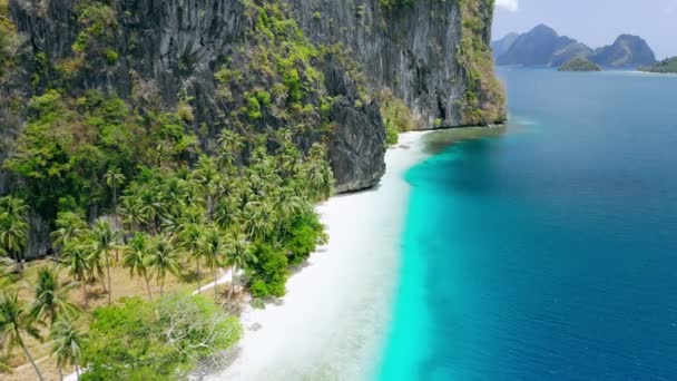 カルスト岩礁とターコイズブルーの海に囲まれた自然のままの熱帯の白い砂浜の空中ドローンの景色ピナグビュータン島エルニド パラワンフィリピン息をのむような風景 — ストック動画