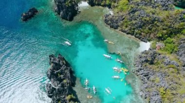 El Nido 'da küçük bir göldeki teknenin havadan aşağı daire görüntüsü Palawan Phillippines banka botları ve kanolar sığ mavi sularda dinleniyor.