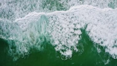 Beyaz dalgaların ve zümrüt yeşili okyanus su yüzeyi drone kuşlarının yukarıdan dalgaların kıyıya doğru kayan görüntülerini içeriyor.