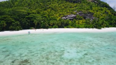 Mükemmel beyaz kumlu turkuaz gölcüklü tropik cennet kumsalının görüntüleri. Yalnız tekne ve yaz tatilindeki çift.