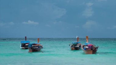 Mavi dalgalarda sallanan dört uzun kuyruklu tekne ufukta beyaz yelkenli teknesi Koh Lipe Tayland 'da