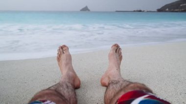 Adamın ayakları kumsalda tatil ve rahatlama konsepti plaj tatillerinde. 