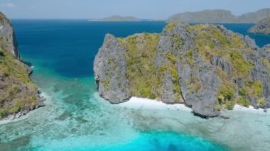 El Nido Palawan 'daki Shimizu Adası' nın hava aracı görüntüleri kayalar ve adanın önündeki sığ turkuaz göl suyu.