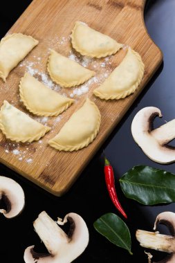 Siyah arka planda tahta bir tahtanın üzerinde yarı bitmiş hamur tatlısı.