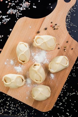 Siyah arka planda tahta bir tahtanın üzerinde yarı bitmiş mantalar.