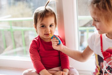 Çocuğunuza covid-19, virüsler ve gribe karşı önleyici önlemler öğretmek. Koruyucu maskeli kız doktorda kız kardeşiyle oynuyor. Sevdiklerinle ilgilen. Sıcaklığı ölçüyoruz..