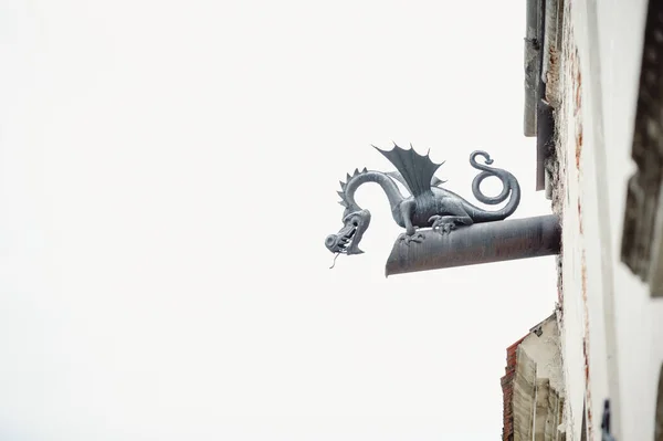 Iron dragon figurine on a waste pipe. Elements of the old city in Gothic style.