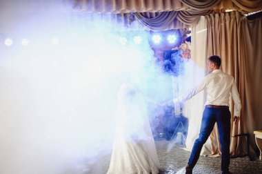 Güzel bir düğün çifti ilk dansları sırasında dumanın içinde durur. Gelin dumanın içinde dans ederken damada doğru kıvrılır. Gelin ve damat restoranda dans ediyor. Düğün çifti duman içinde dans ediyor.