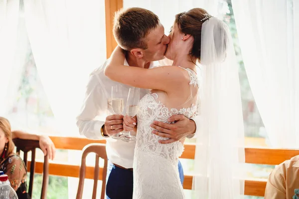 Νύφη Και Γαμπρός Φιλιούνται Πίνοντας Ένα Ποτήρι Σαμπάνια Ένα Τραπέζι — Φωτογραφία Αρχείου