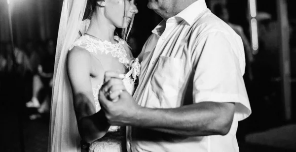 Attractive  bride is dancing with her father at the wedding on the terrace. The bride is dancing with her dad. Wedding banquet. Black and white photo. Film grain