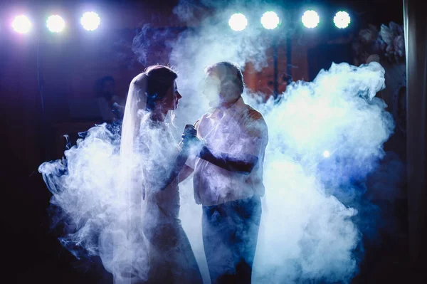 An attractive bride dances with her father at a wedding in the cold smoke that creeps across the ground. The bride is dancing with her dad. Wedding banquet. Film grain