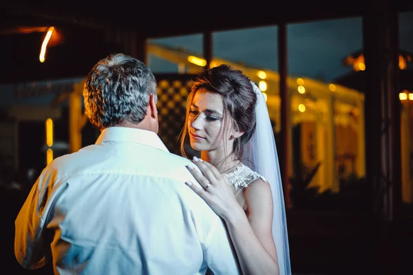 Attractive bride dancing with her father at a wedding on the terrace. The bride is hugging her dad at a wedding ceremony. Wedding banquet.