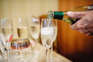 Kristal bardağa şampanya döküldü. Erkek el büyük bir şişe tutuyor.