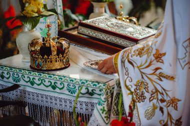 Rahip düğün töreni için hazırlanıyor. Altın taçlar, İncil ve nikah masasında mihrapta alyans. Geleneksel dini düğün töreni