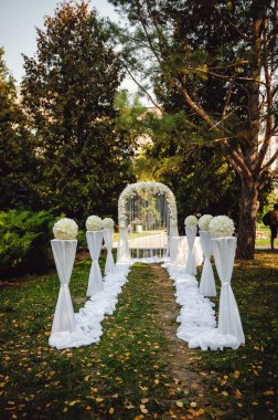 Düğün alayının kavisine açık havada çiçekler ve sütunlar takıldı. Düğün dekoru. Fotoğraf Bölgesi. Dikey fotoğraf.