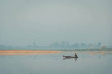 Sis, ot, göllerin ve doğanın arka planındaki ağaçlar. Teknede balık tutmak balık tutar. Gölde, nehirde sisli bir sabah. Gün doğumu, balık tutma. Kırsal kesimde yaz manzarası