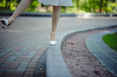 Elbiseli mutlu bir kız ve parkta yürüyen şık beyaz ayakkabılar. Romantik kız. Metin için yer