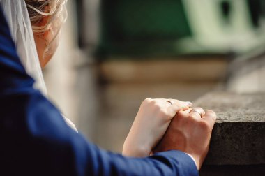 Gelin ve nişanlı düğün töreninde el ele tutuşuyorlar. Kocasının ve karısının parmağında evlilik yüzüğü var. Metin için yer