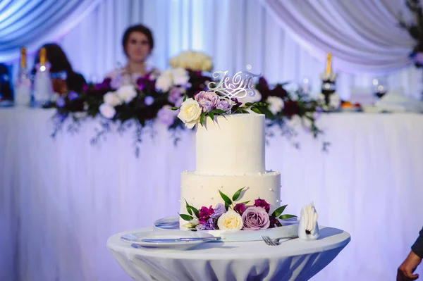 White, multi-storey wedding cake with flowers for a wedding banquet. Delicious wedding reception. Celebration party concept. Fashionable cake.