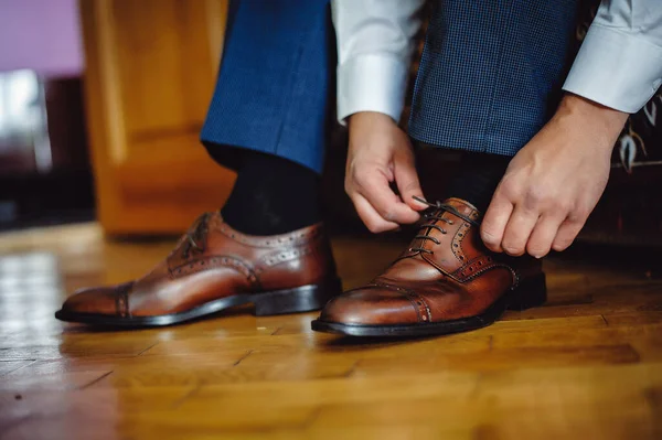 The groom morning before wedding ceremony wears shoes. Businessman tie the laces on the shoes. Men\'s style. Professions. To prepare for work, to the meeting.