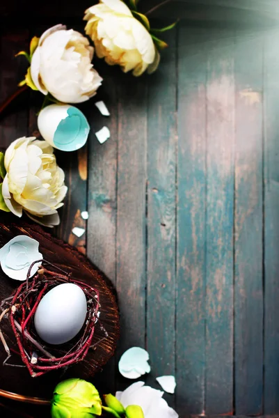 Weißes Ei in kleinem Nest mit hellen Blumen auf rustikalem Holzgrund. Osterfrühlingskonzept — Stockfoto