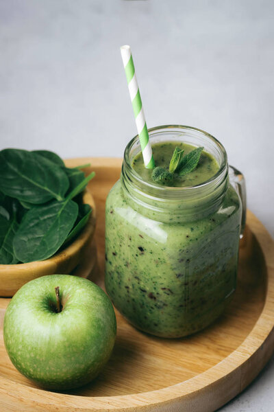 Healthy breakfast, green smoothie in a glass jar and some ingredients - spinach and apple. Superfood, detox food