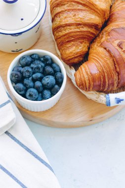 Lezzetli kahvaltı taze kruvasanlar ve açık renkli, parlak taze ruh üzerinde yaban mersini ile