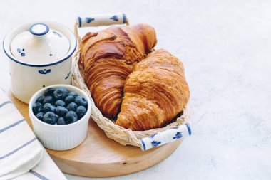 Lezzetli kahvaltı taze kruvasanlar ve açık renkli, parlak taze ruh üzerinde yaban mersini ile