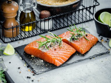 İki adet taze ot biberiye, baharat ve siyah arduvaz plaka üzerinde zeytin yağı ile Çiğ somon fileto