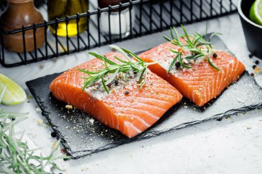 İki adet taze ot biberiye, baharat ve siyah arduvaz plaka üzerinde zeytin yağı ile Çiğ somon fileto