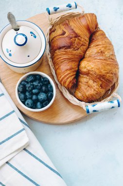 Lezzetli kahvaltı taze kruvasanlar ve açık renkli, parlak taze ruh üzerinde yaban mersini ile