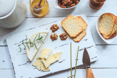 Peynir tabağı kraker, bal ve fındık ile servis. Camembert Beyaz ahşap beyaz doku arka plan üzerinde kurulu hizmet. Meze Tema. Üstten Görünüm