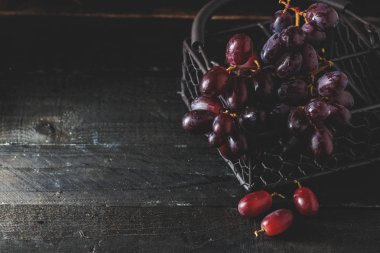Siyah ahşap zemin, karanlık ruh üzerine metalik sepet içinde kırmızı üzüm