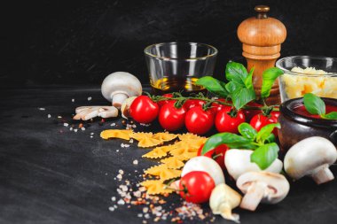 İtalyan pasta malzemeler. Domates, farfalle makarna, sarımsak, mantar, fesleğen, zeytinyağı, mozzarella ve baharat karanlık grunge zemin üzerinde