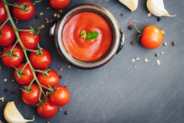 Salsa de ketchup de tomate en un bol con especias, ajo y tomates cherry sobre fondo oscuro. Vista desde arriba . — Foto de Stock