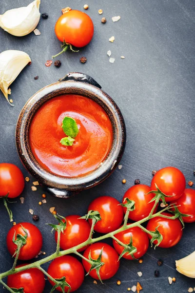 Salsa de ketchup de tomate en un bol con especias, ajo y tomates cherry sobre fondo oscuro. Vista desde arriba . — Foto de Stock