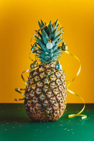 Ananas versierd met serpentijn en ballen, kerstvakantie en nieuwjaarsconcept — Stockfoto