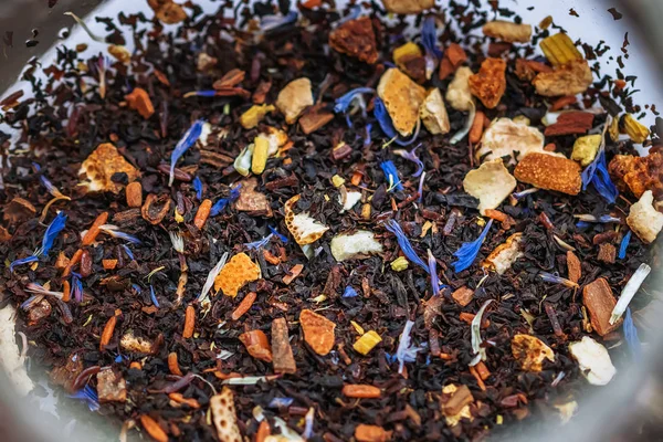 Kışa yakın siyah çay karıştırın tropik meyve ve mısır çiçekleri ve baharatlar bir çaydanlıkta — Stok fotoğraf