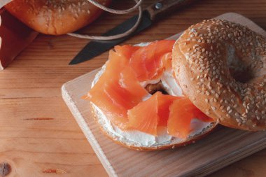 Eski ahşap masada taze somonlu simit.