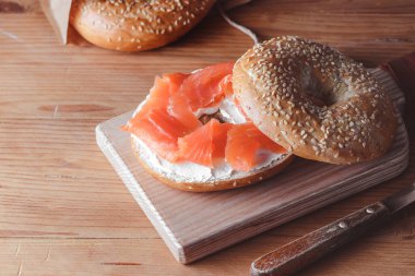 Eski ahşap masada taze somonlu simit.