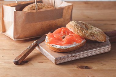 Eski ahşap masada taze somonlu simit.
